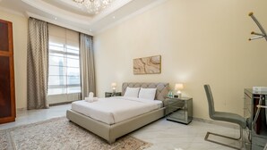 Une chambre spacieuse avec un grand lit, un lustre et un fauteuil moderne.