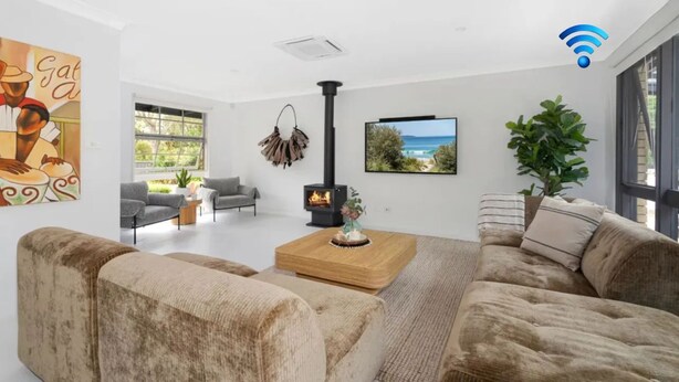 Una sala de estar moderna con chimenea, asientos cómodos, un ventanal grande y un cuadro en la pared.