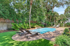 A backyard with a swimming pool, two lounge chairs, and a wooden fence. - Near Beach Rental with Private Heated Pool & Putting Green | Isle of Palms (Isle of Palms)
