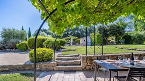 An outdoor patio with a table and chairs, stone steps leading to a house, and a garden with various plants and a lawn. - les Marcellines, character property with heated swimming pool and views (Saint-Restitut)