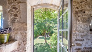 An open doorway leading to a garden with a lawn, trees, and a potted plant on the left. - les Marcellines, character property with heated swimming pool and views (Saint-Restitut)