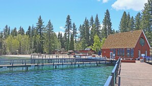 A wooden dock extending into a lake, surrounded by dense forest. A red building with large windows and a triangular roof is visible on the right. - Chambers Dreamin'-Chambers Beach, Pool & Tennis, Beautiful 3 bedroom, 2 bath (Homewood)