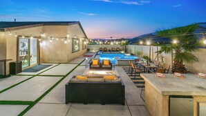 A pool area with lounge chairs, a dining table, and string lights. - New Pool+Spa+Games+Large BBQ+Designer+Beautiful (Coachella)