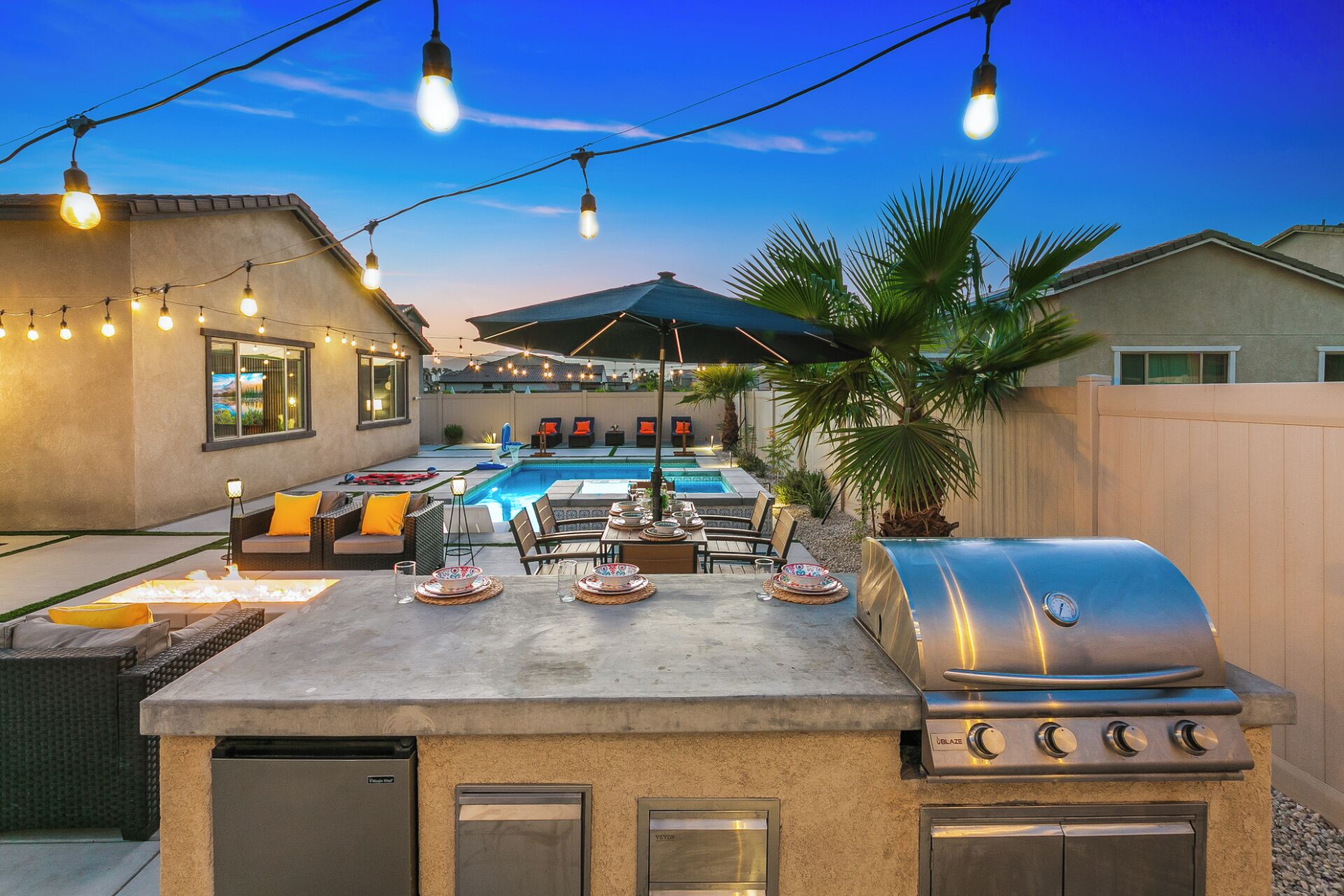 An outdoor patio with a barbecue grill, dining table, and chairs.