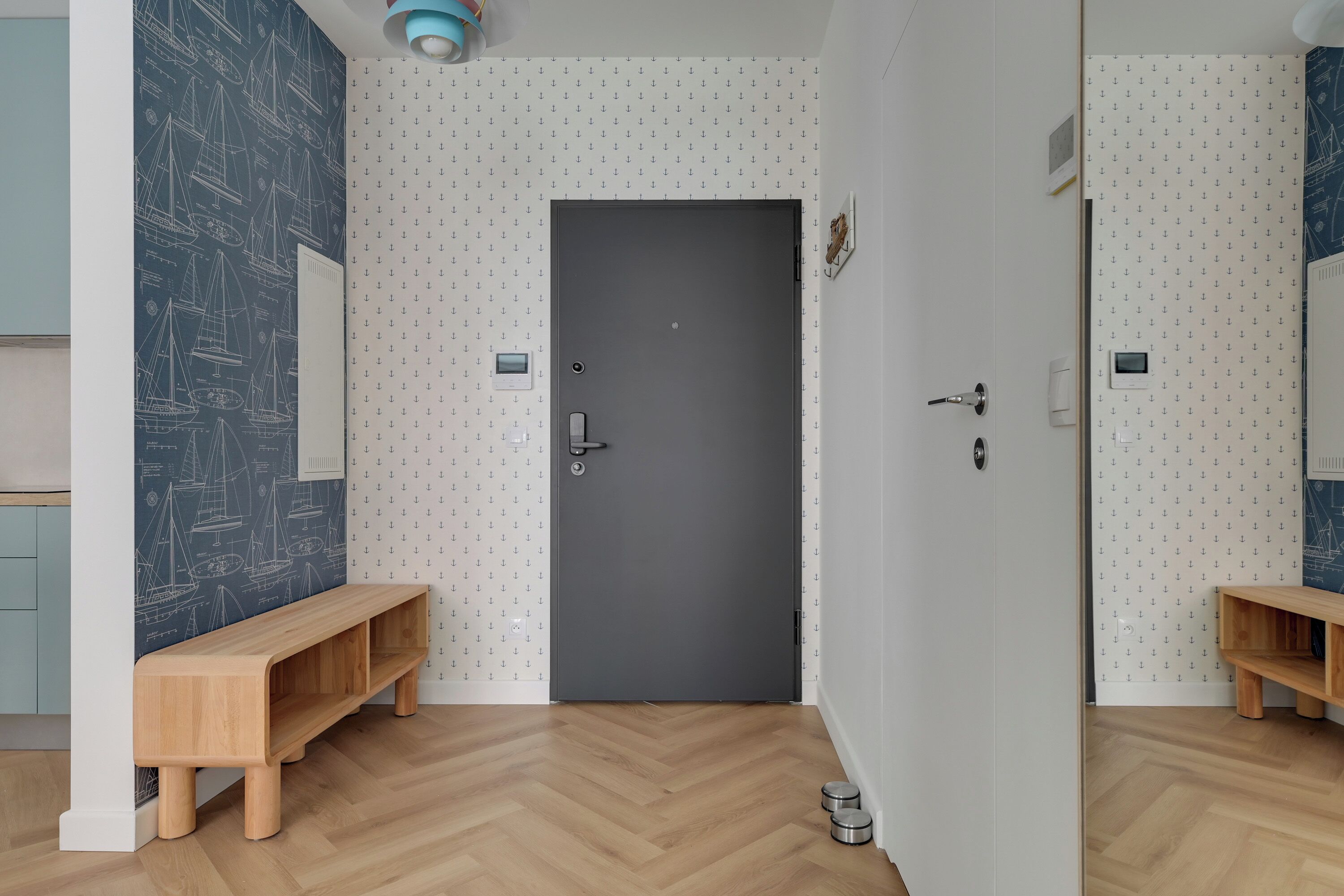 A modern room with a grey door, wooden benches, and patterned wallpaper.