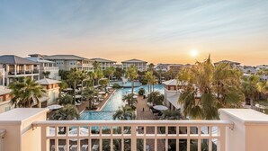 Ein Resort mit Schwimmbad, Palmen und Blick auf den Sonnenuntergang.