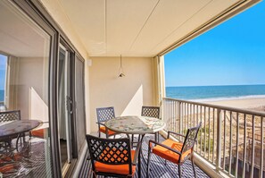 A balcony with a table and chairs, a view of the beach, and a door leading to another room. - Sandpiper Dunes 702(Side View) (Ocean City)