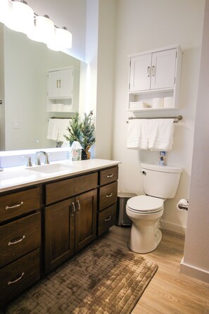 A bathroom with a white sink, dark wooden vanity, white toilet, and a mirror above the sink.