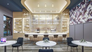 A modern bar area with a central island, bar stools, and a laptop on a table. - Bennet at Bullstreet (Columbia)