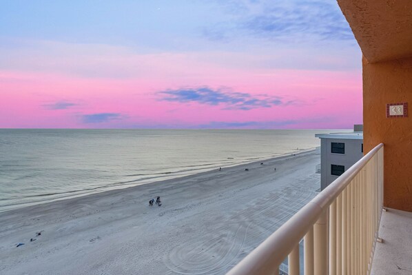 A beach view from a balcony with a clear sky and calm sea.