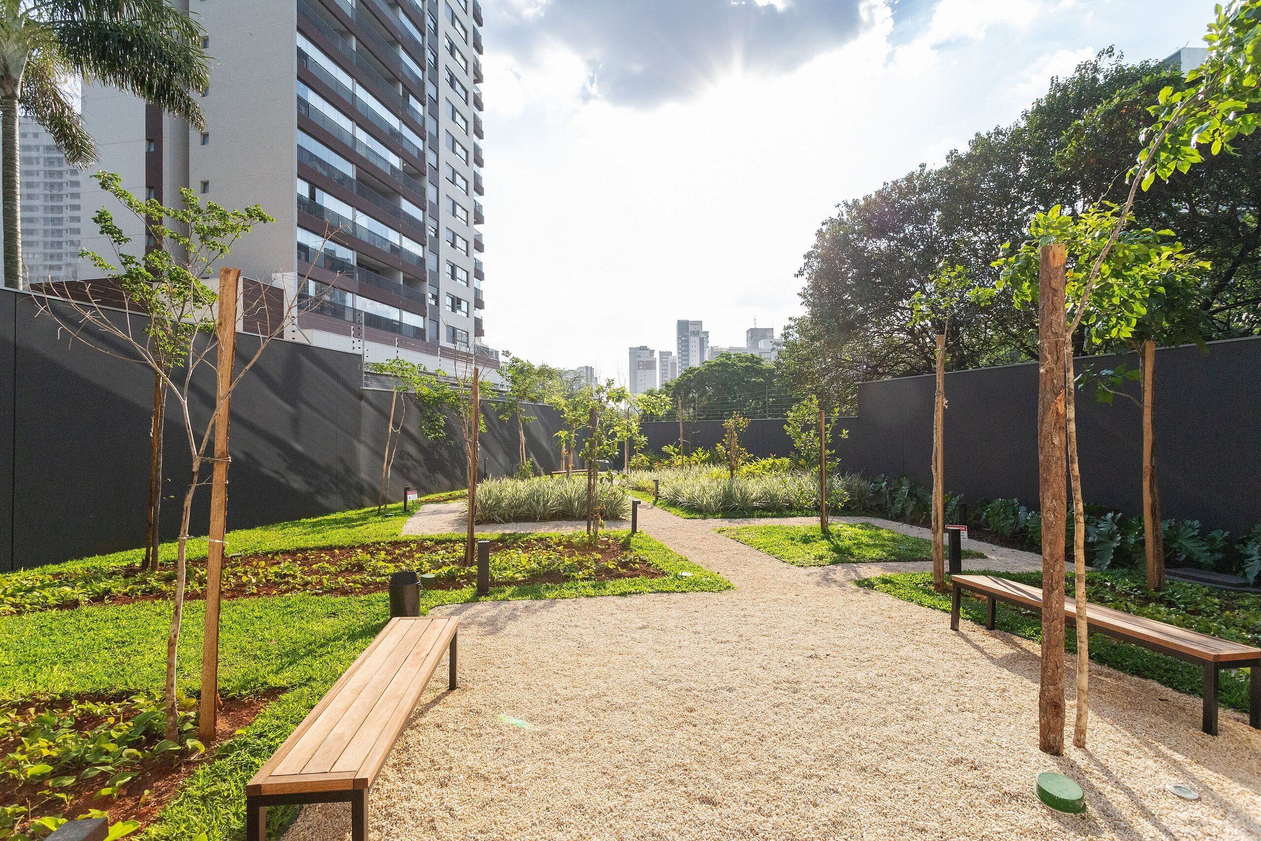 An outdoor garden area with pathways, benches, and young trees.