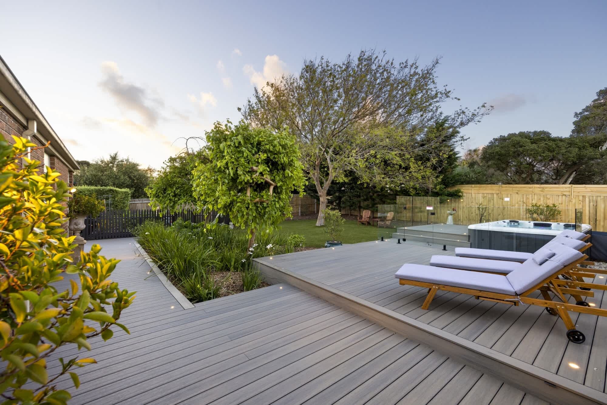 Une terrasse en bois avec des chaises longues et un jacuzzi.