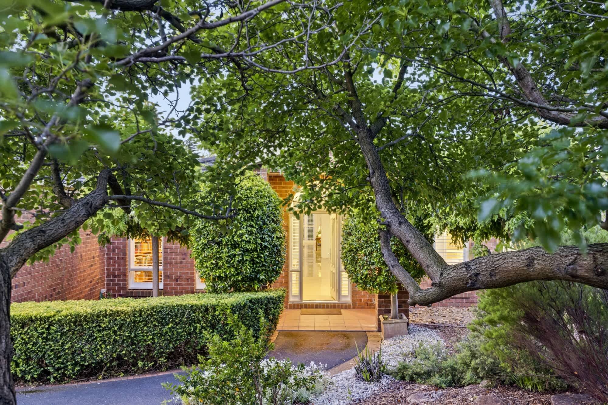 A brick building with a well-maintained hedge and a paved pathway leading to the entrance.