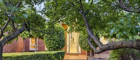 A brick building with a well-maintained hedge and a paved pathway leading to the entrance.
