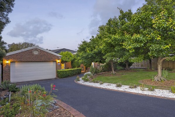 A residential driveway leading to a garage with a brick facade and a covered entryway.