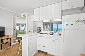 Una cocina moderna con armarios blancos, estufa integrada y un refrigerador con un mapa.