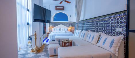 Ein Schlafzimmer mit einem großen Bett, einer Couch, einem Deckenventilator und einem Fernseher.