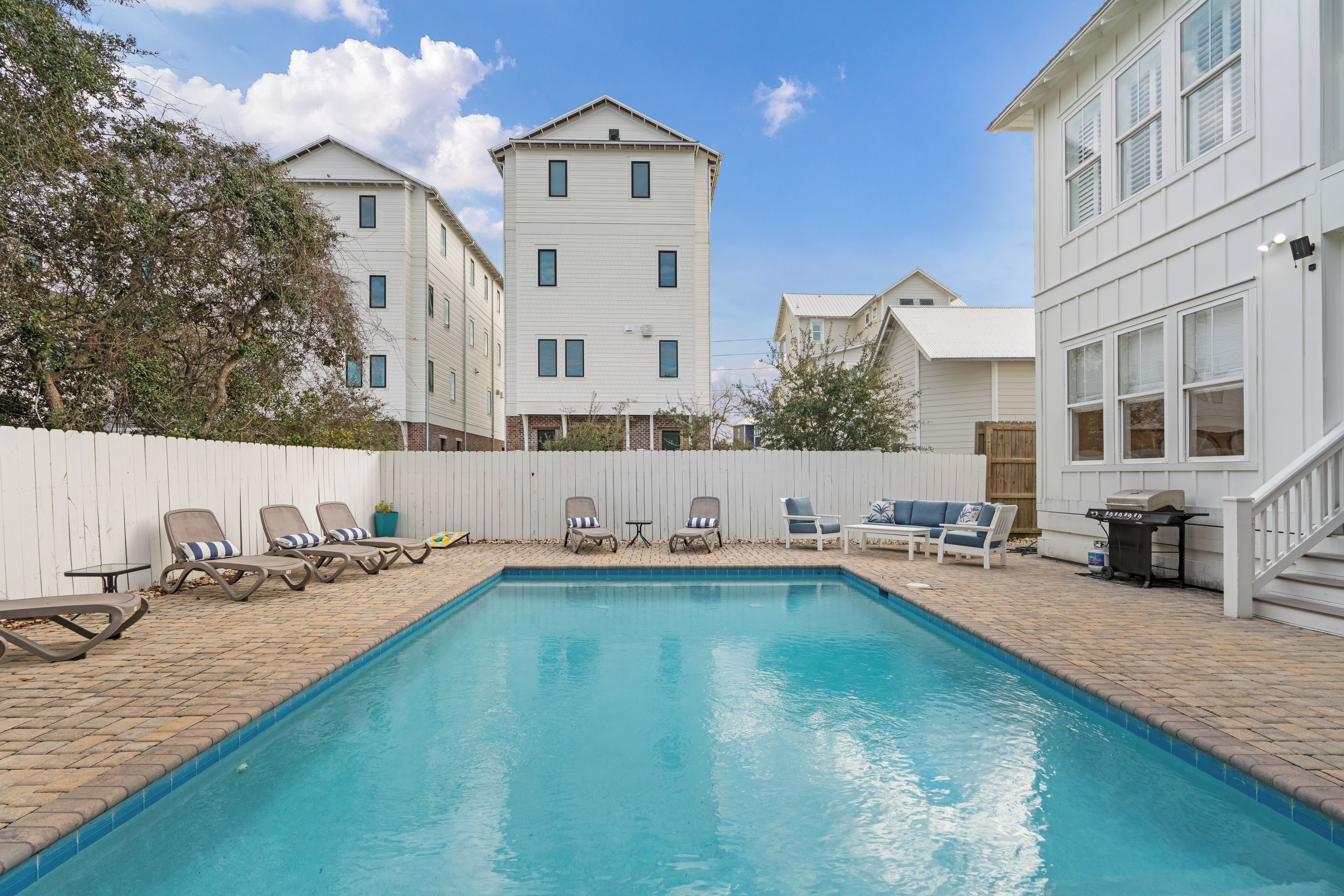A rectangular swimming pool with lounge chairs and a barbecue grill.