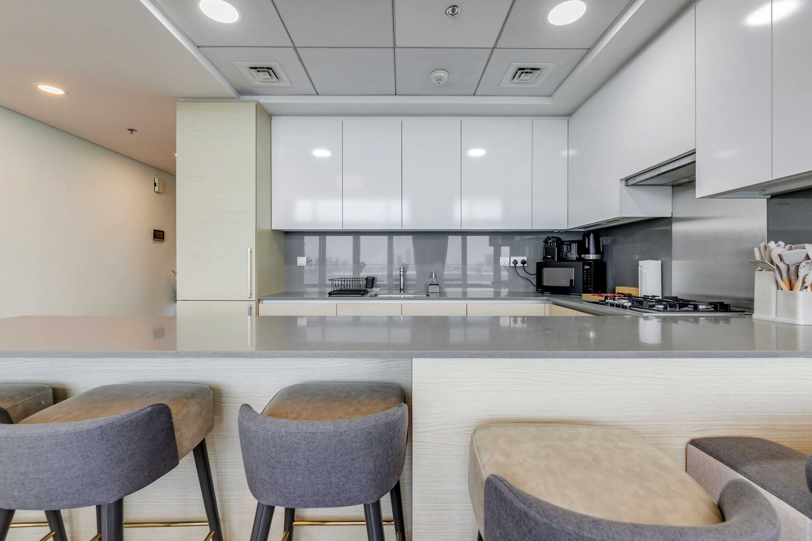 A modern kitchen with a central island, bar stools, and stainless steel appliances.
