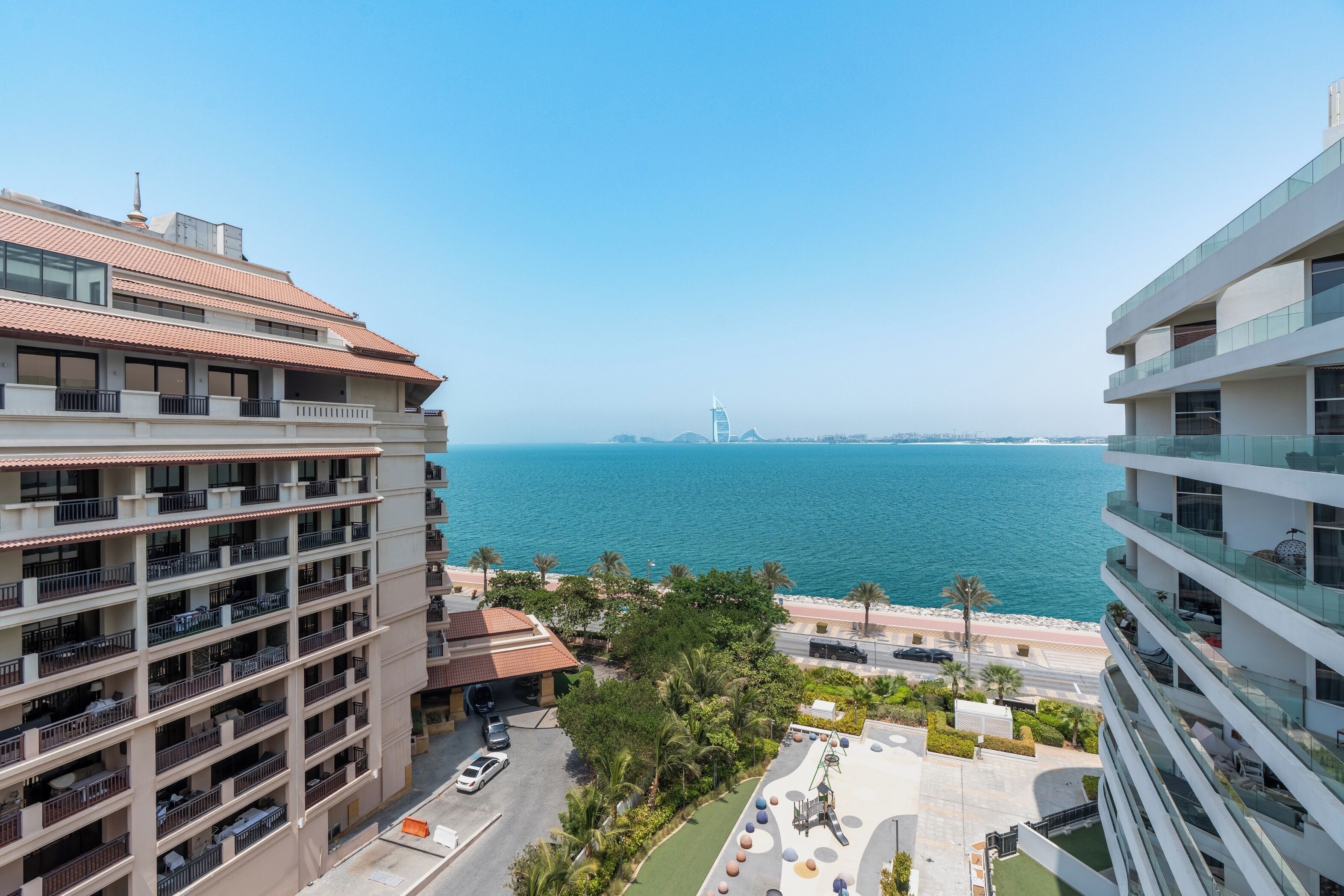 A high-rise building with multiple balconies overlooking a coastal area.