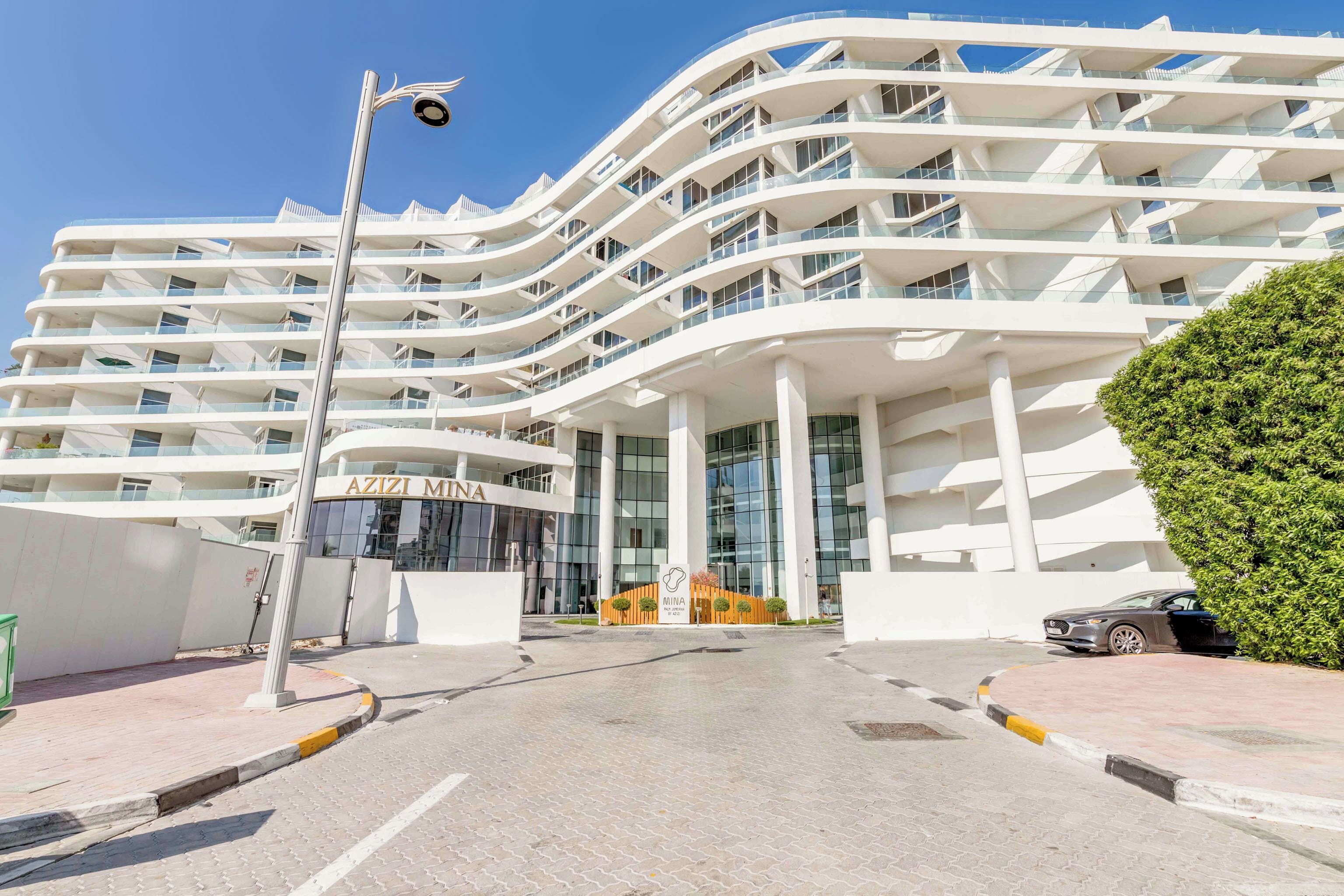 Un hôtel moderne à la façade incurvée, doté de nombreux balcons et d’une entrée imposante.