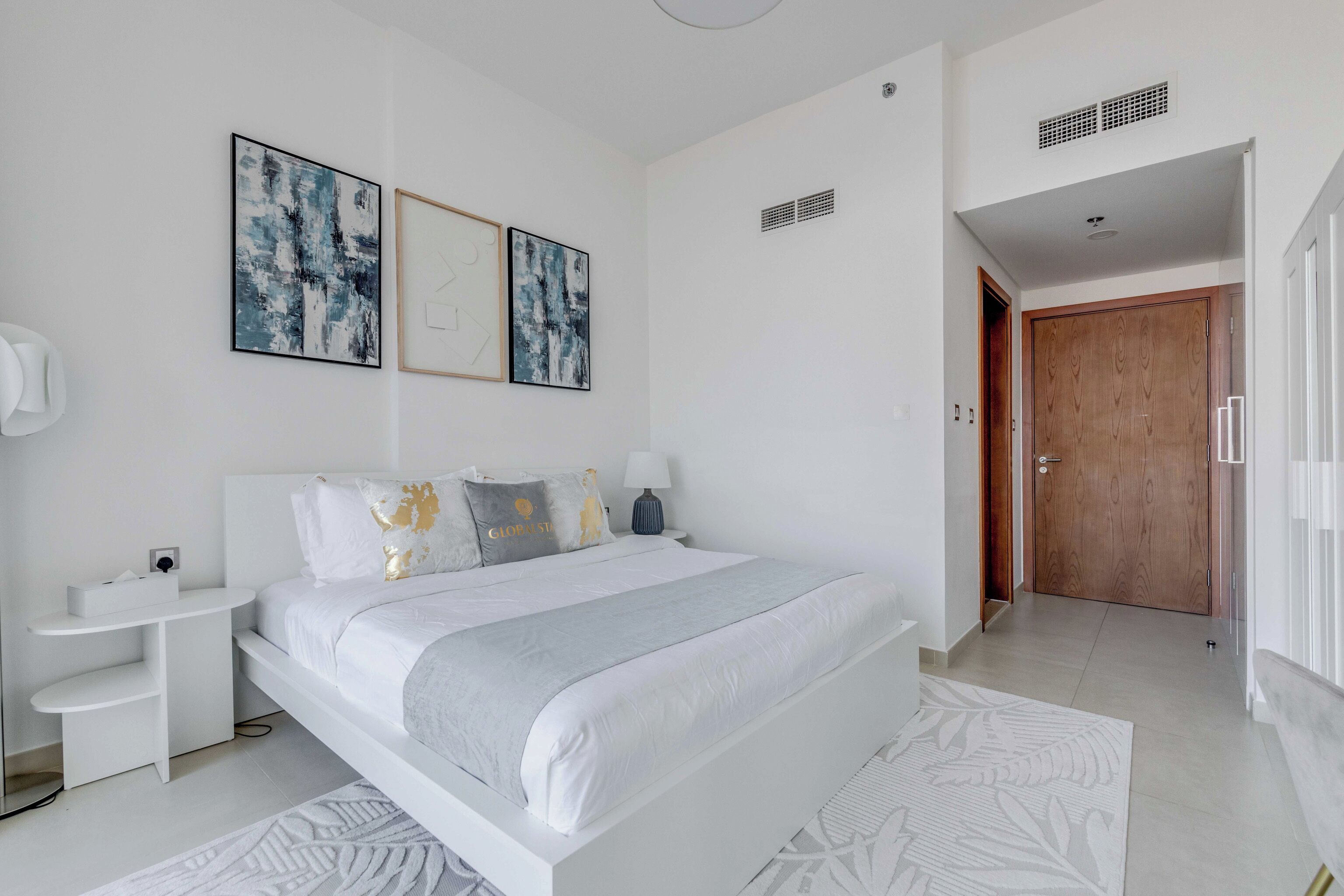 A modern bedroom with a large bed, bedside tables, and artwork on the wall.