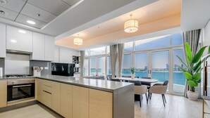 A modern kitchen with a central island, built-in appliances, and large windows offering a view of the sea. - Globalstay Luxury Azizi Mina Beachfront  (Dubai)