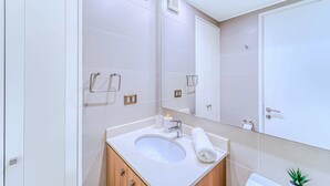 A modern bathroom with a large mirror, a sink, and a towel rack. - Rincon Miramar (Concón)