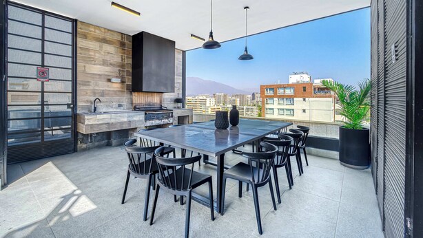 A rooftop terrace with a dining area, a grill, and a view of the cityscape. - Espacio Nunoa 1BR, balcony and free parking (Ñuñoa)