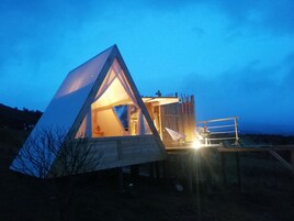 Estructura en forma de cúpula geodésica con entrada triangular y un pequeño balcón.