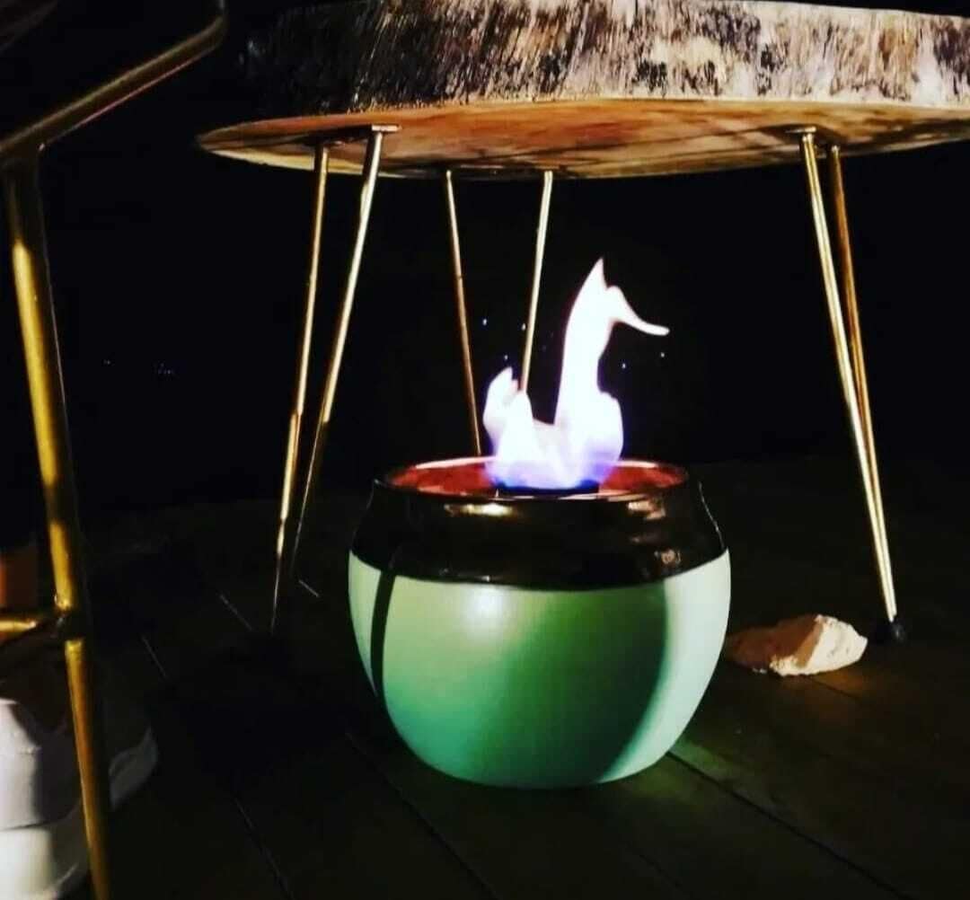 Una mesa con un cuenco verde encima, un objeto blanco en la parte superior y una llama debajo.