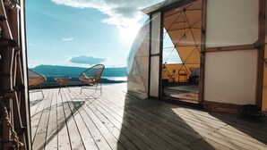Un pontile in legno con due sedie e un tavolo, affacciato su un paesaggio montuoso.
