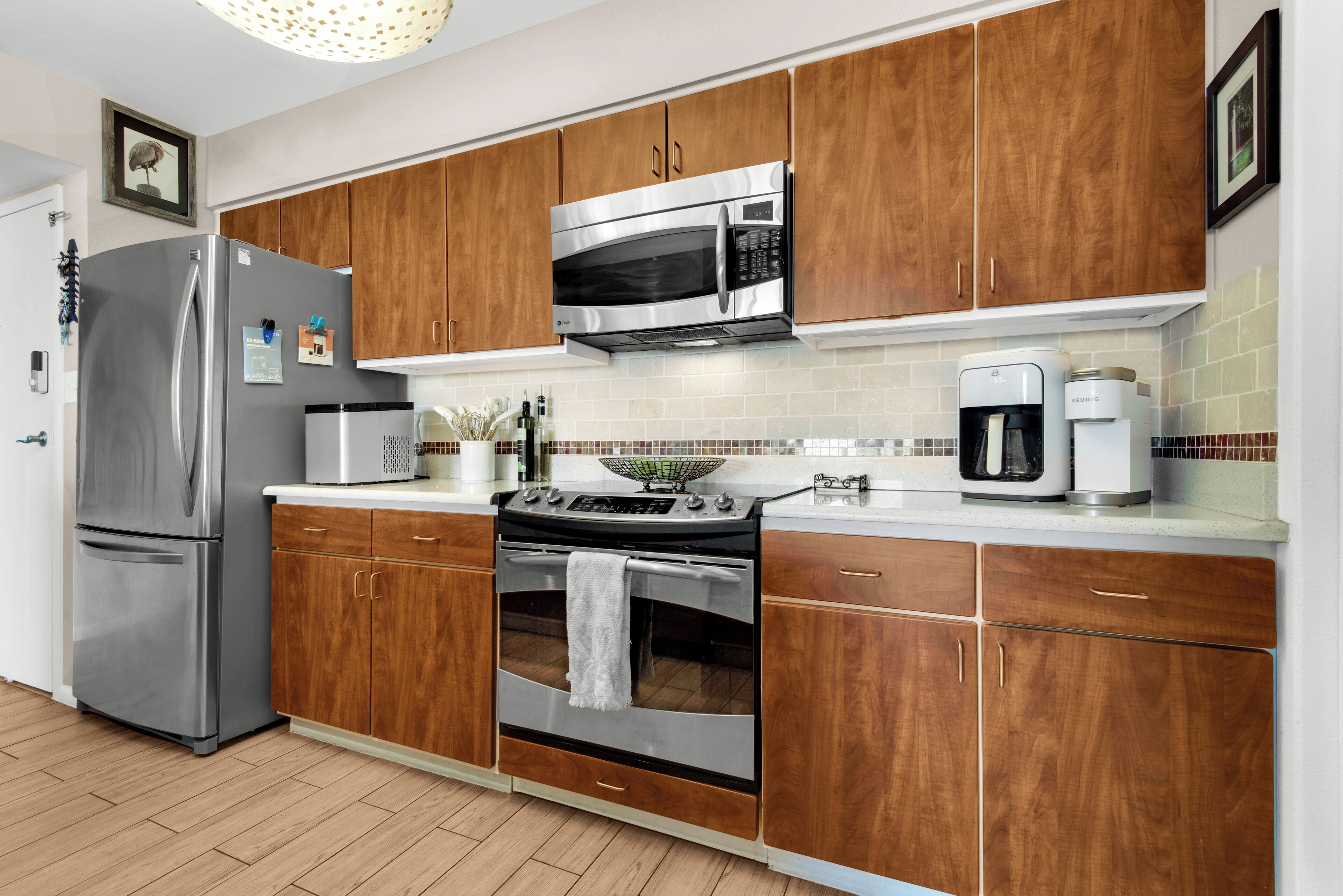 A modern kitchen with stainless steel appliances, wooden cabinets, and a tiled backsplash.