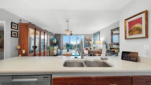 Una cocina moderna con una isla grande, pileta de acero inoxidable, muebles de madera y vistas al exterior.