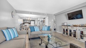 A modern living room with a sofa, coffee table, and a television. - 🏝️Sound Views | Walk to Beach☀️ Santa Rosa Dunes 722 (Pensacola Beach)