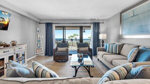 A living room with a sofa, chairs, a coffee table, and a view of the ocean. - 🏝️Sound Views | Walk to Beach☀️ Santa Rosa Dunes 722 (Pensacola Beach)