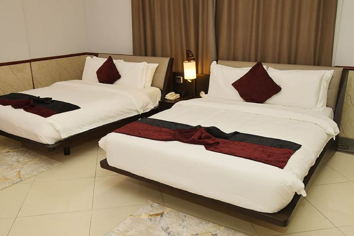 Two twin beds with white bedding and dark red throw pillows in a hotel room.