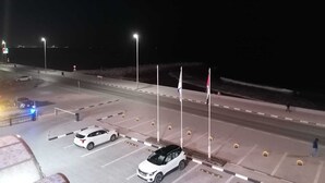 A nighttime parking area with multiple cars, streetlights, and flags. - Claridge Star Hotel (Ras Al Khaimah)