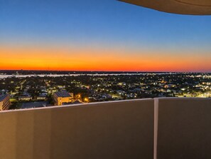 A cityscape at dusk with a clear view of the horizon and a balcony overlooking the area.