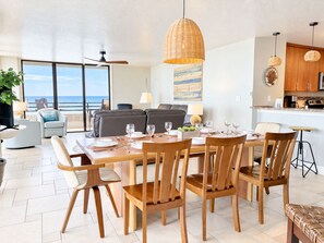A modern dining area with a large table set for six, surrounded by wooden chairs.