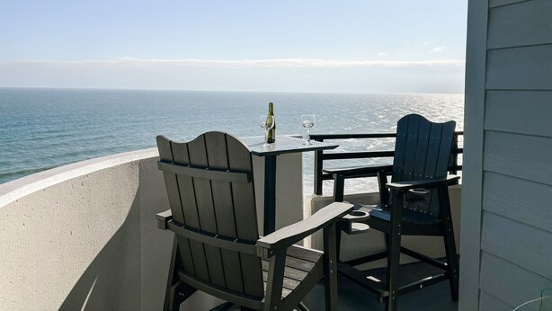 A balcony with a table and chairs overlooking the ocean. - Oceanfront Condo Wraparound Balcony Sunrise Views (Daytona Beach)