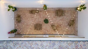 Una habitación amplia con piso de madera en patrón de espiga, una planta verde en el centro y varias bancas de madera.