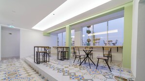 Un interior moderno con suelo estampado, mesas, sillas y ventanas amplias.
