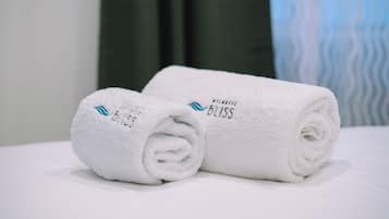 To sammenrullede hvide håndklæder med teksten "BATHROOM BLISS" på en hvid overflade.
