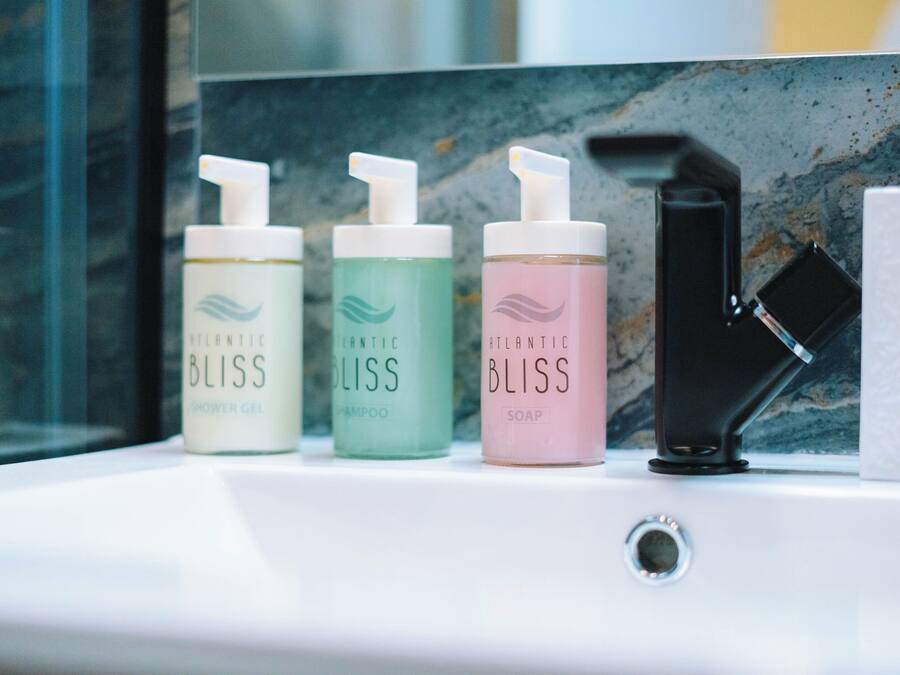 A bathroom sink with three bottles of Atlantic Bliss products: shower gel, shampoo, and soap.