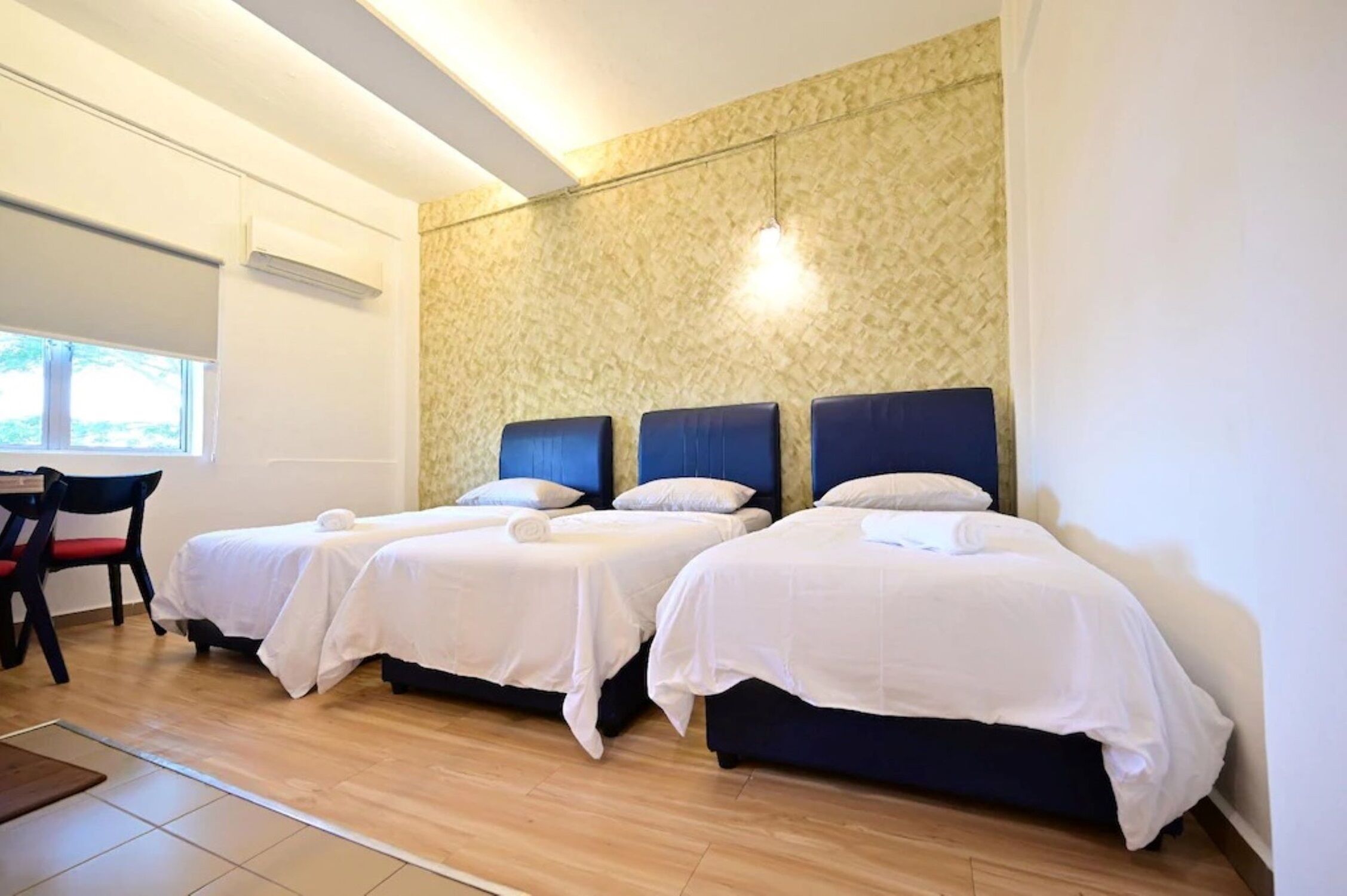 A hotel room with two single beds, a desk, and a chair.