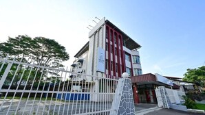 A modern building with a gated entrance, a staircase, and a covered area with a glass facade. - First Star Homestay (Kluang)