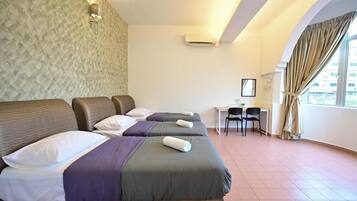 Camera d'albergo con due letti, una scrivania, sedie e un'ampia finestra con tende.