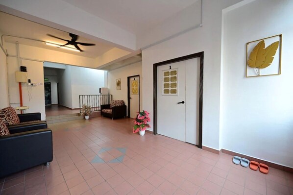 A spacious hallway with a ceiling fan, a sofa, a chair, a door, and a potted plant.