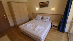 A hotel room with a large bed, two bedside tables, a wardrobe, and a painting on the wall. - Menada Paradise Dreams Apartments (Sveti Vlas)